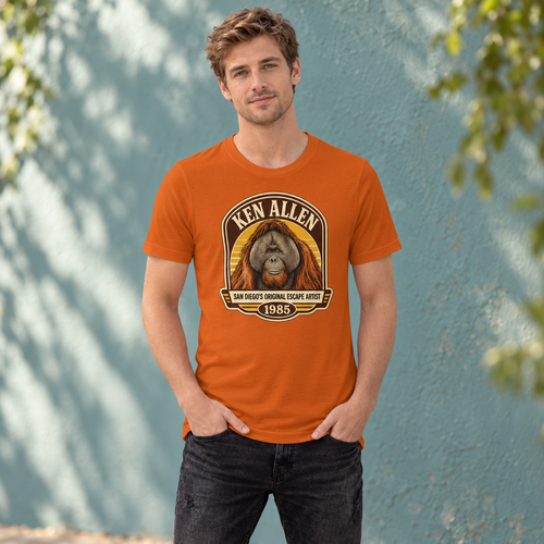 Autumn Ken Allen Heritage tee with retro orangutan badge artwork against a teal courtyard wall