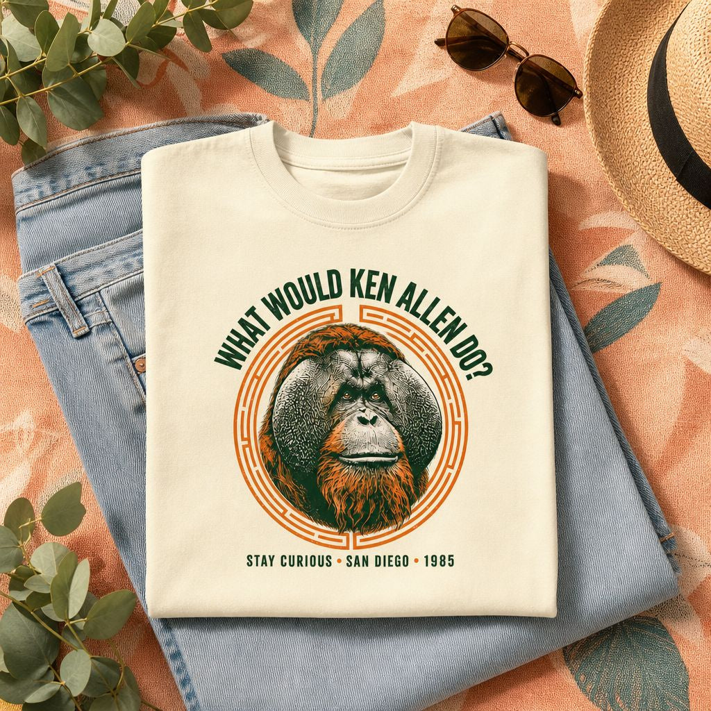 Folded Natural What Would Ken Allen Do? tee with orange orangutan artwork styled with blue jeans, sunglasses, a straw hat and greenery